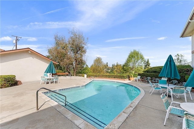 community pool with a patio area and outdoor dining area