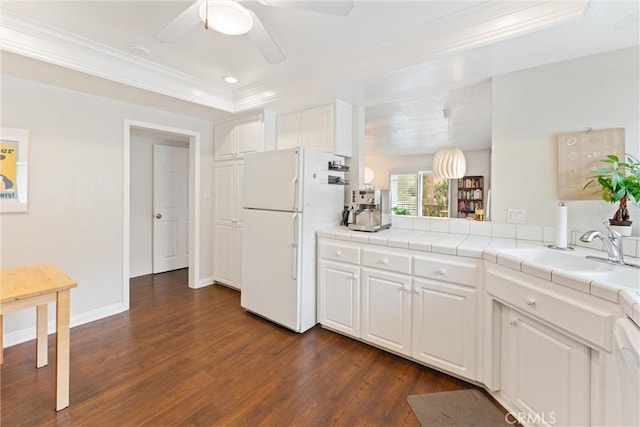 kitchen featuring freestanding refrigerator, crown molding, dark wood-style floors, tile counters, and a ceiling fan
