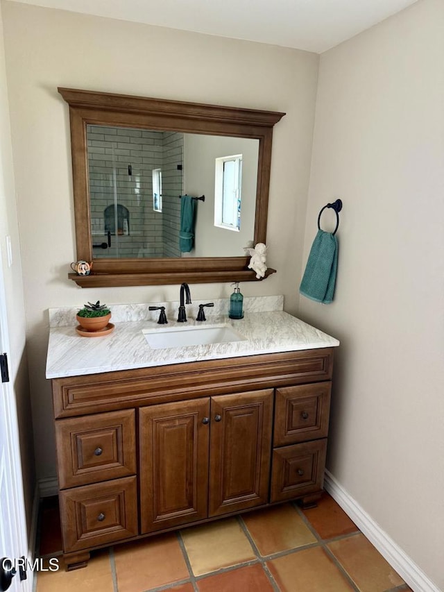 bathroom with baseboards, tile patterned flooring, vanity, and tiled shower
