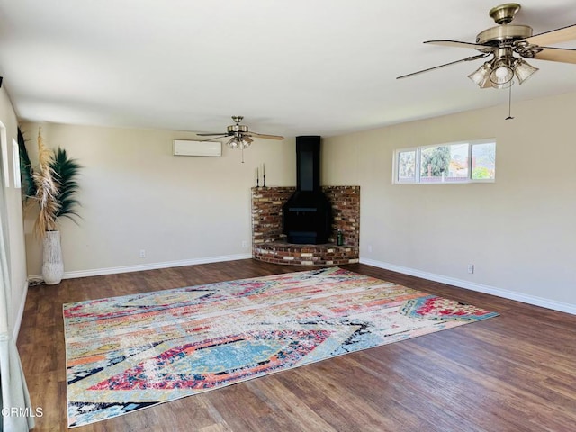 living area featuring a ceiling fan, a wood stove, baseboards, and wood finished floors