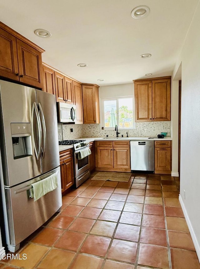 kitchen with light countertops, appliances with stainless steel finishes, brown cabinets, and backsplash