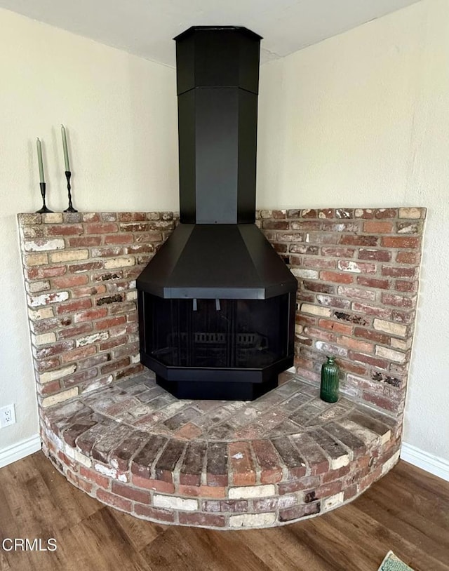 room details with baseboards, a wood stove, and wood finished floors