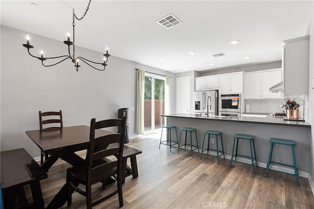 dining space with a chandelier, light wood-type flooring, visible vents, and recessed lighting