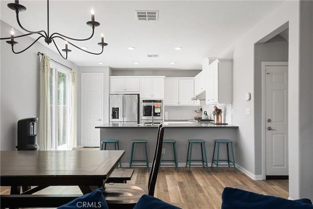 kitchen featuring dark countertops, stainless steel appliances, a peninsula, and visible vents