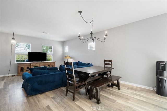 dining room featuring an inviting chandelier, visible vents, light wood-style flooring, and baseboards