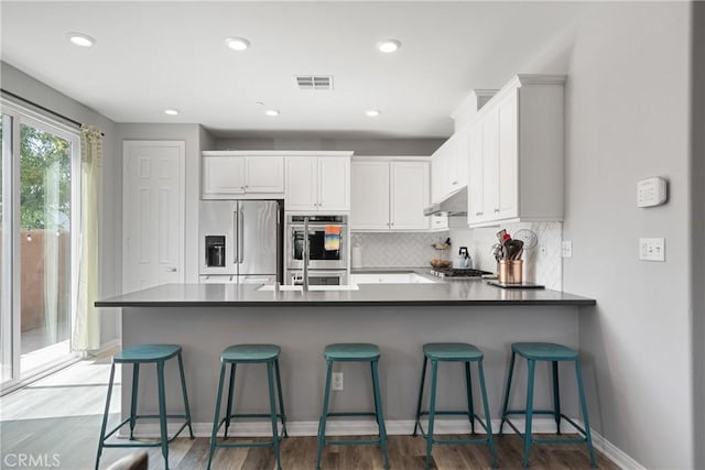 kitchen featuring stainless steel appliances, a peninsula, visible vents, and white cabinets