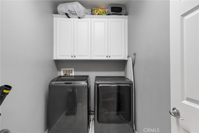clothes washing area featuring independent washer and dryer and cabinet space