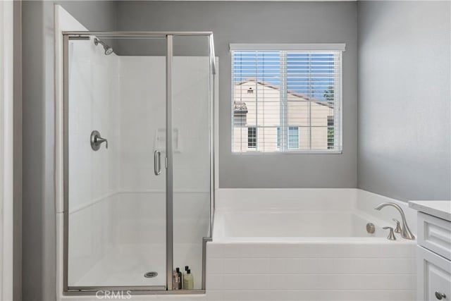 bathroom featuring a stall shower, vanity, and a bath