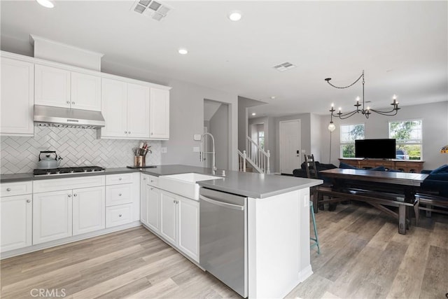 kitchen with a sink, open floor plan, visible vents, under cabinet range hood, and dishwasher