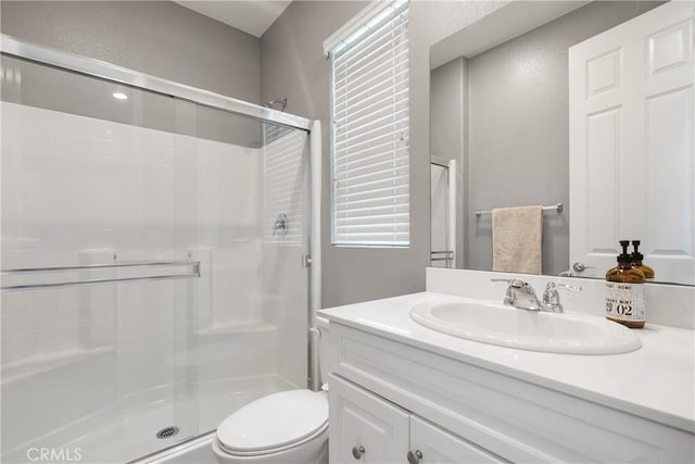 bathroom with vanity, toilet, and a shower stall