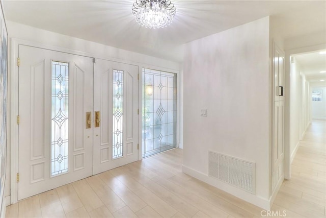 entrance foyer featuring a chandelier, light wood-style floors, and baseboards