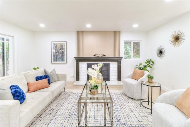 living area featuring a glass covered fireplace, recessed lighting, baseboards, and wood finished floors