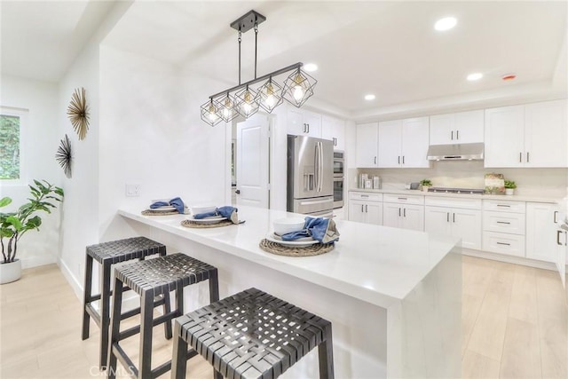 kitchen featuring stainless steel appliances, under cabinet range hood, white cabinets, a peninsula, and light countertops