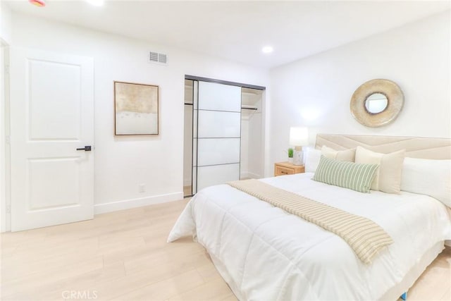 bedroom with baseboards, light wood-type flooring, recessed lighting, and a closet
