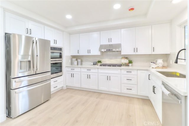 kitchen with appliances with stainless steel finishes, a sink, under cabinet range hood, recessed lighting, and white cabinetry