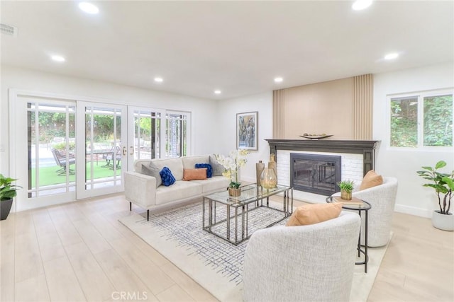 living room featuring plenty of natural light, a brick fireplace, french doors, recessed lighting, and wood finished floors