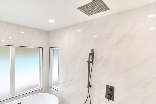full bathroom featuring a freestanding bath and a marble finish shower