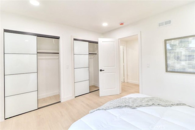 bedroom featuring multiple closets, light wood finished floors, and recessed lighting