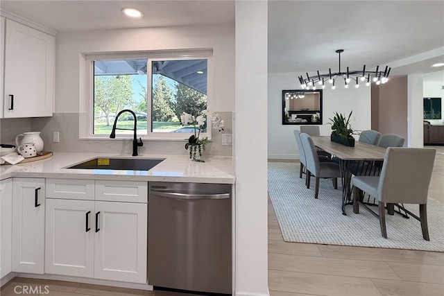 kitchen with stainless steel dishwasher, a sink, white cabinets, decorative backsplash, and recessed lighting