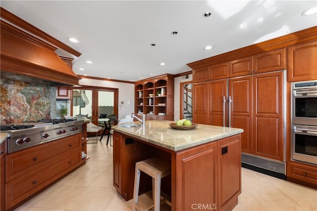 kitchen with stainless steel appliances, recessed lighting, an island with sink, custom exhaust hood, and crown molding