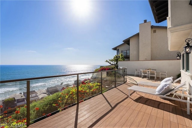 balcony featuring a beach view, a water view, and outdoor dining space