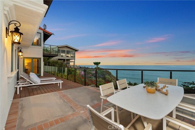 balcony with a water view and outdoor dining area