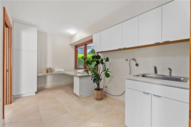 washroom with washer hookup, light tile patterned floors, baseboards, and a sink