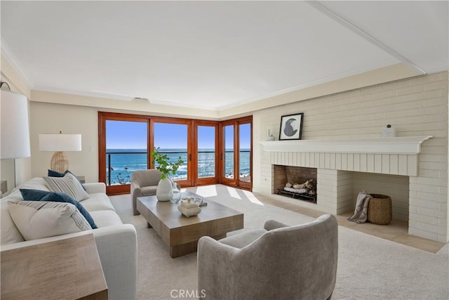living area with carpet flooring, crown molding, a water view, and a fireplace