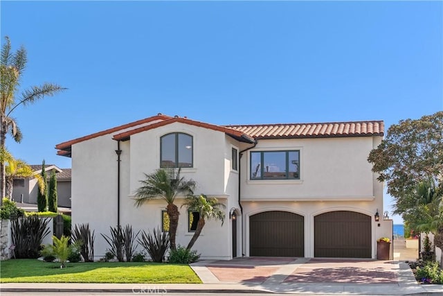 mediterranean / spanish house with driveway, stucco siding, and an attached garage