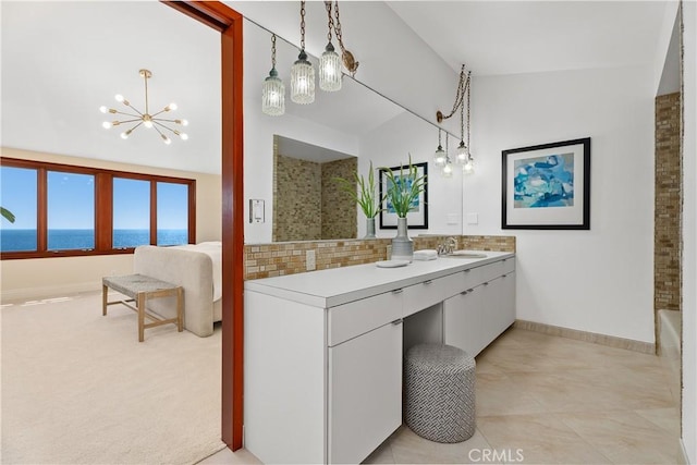 bathroom with a water view, a notable chandelier, baseboards, backsplash, and vanity