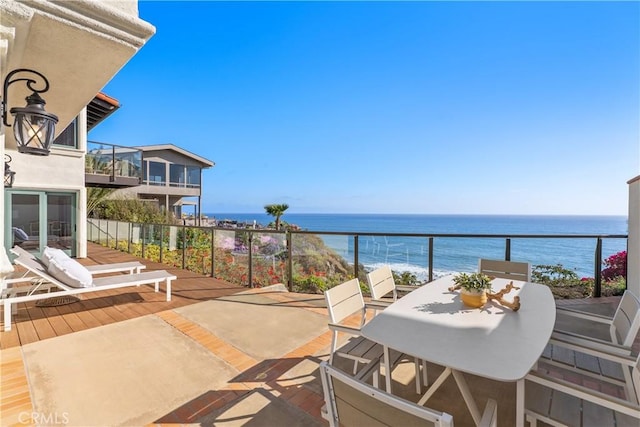 balcony with a water view and outdoor dining space
