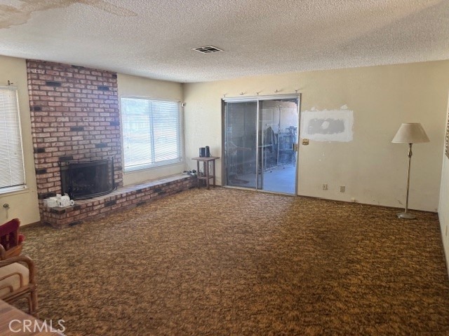 14122 Pawnee Rd, Apple Valley, CA 92307 - carpeted living room featuring a textured ceiling and a brick fireplace