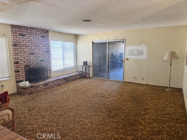 14122 Pawnee Rd, Apple Valley, CA 92307 - living area with carpet, a textured ceiling, and a brick fireplace