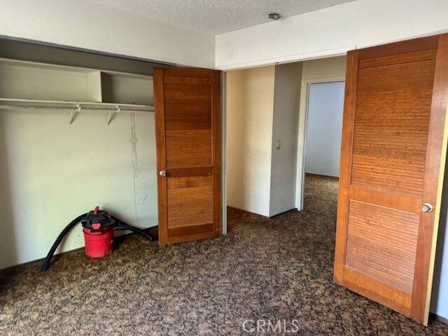14122 Pawnee Rd, Apple Valley, CA 92307 - unfurnished bedroom with carpet floors, a textured ceiling, and a closet