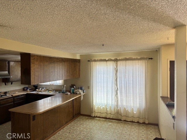 14122 Pawnee Rd, Apple Valley, CA 92307 - kitchen with a peninsula, a textured ceiling, and under cabinet range hood