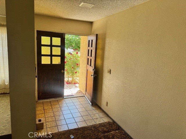 14122 Pawnee Rd, Apple Valley, CA 92307 - foyer entrance featuring a textured wall, a textured ceiling, and light tile patterned floors