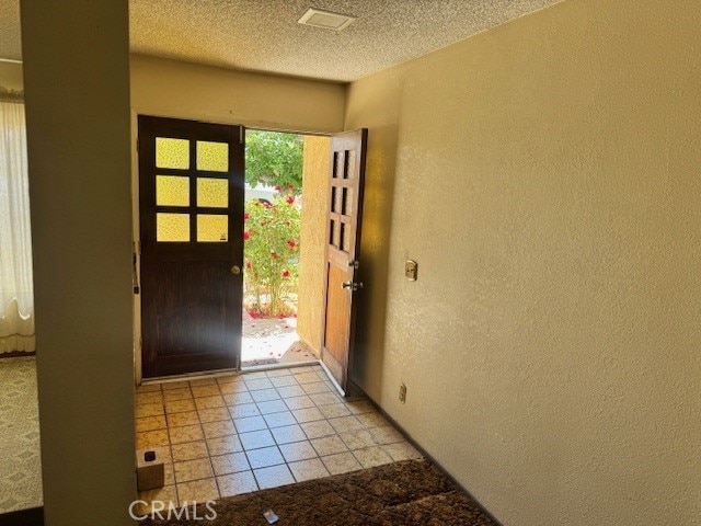 14122 Pawnee Rd, Apple Valley, CA 92307 - foyer entrance with a textured wall, a textured ceiling, and light tile patterned flooring