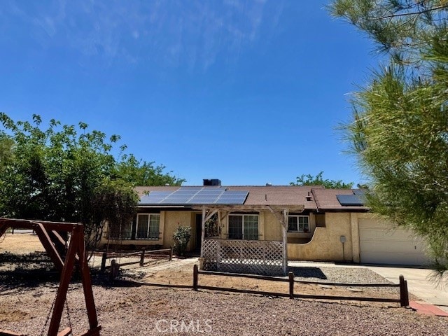 14122 Pawnee Rd, Apple Valley, CA 92307 - back of property featuring an attached garage, roof mounted solar panels, stucco siding, fence, and driveway