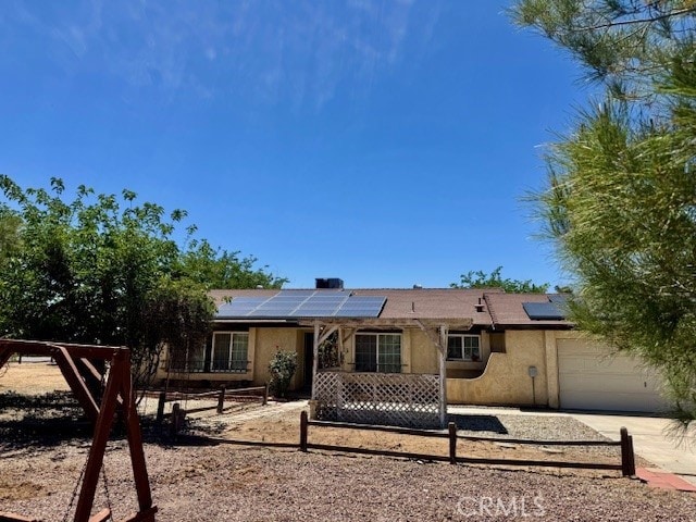 14122 Pawnee Rd, Apple Valley, CA 92307 - back of house with an attached garage, roof mounted solar panels, stucco siding, and concrete driveway