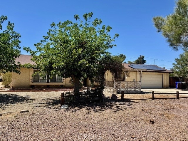 14122 Pawnee Rd, Apple Valley, CA 92307 - obstructed view of property with solar panels, fence, an attached garage, driveway, and stucco siding