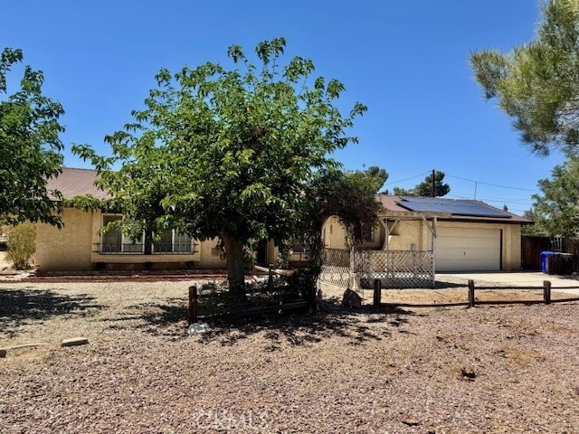 14122 Pawnee Rd, Apple Valley, CA 92307 - obstructed view of property featuring solar panels, a garage, driveway, and stucco siding