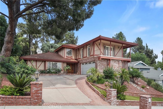 11300 Dulcet Ave, Porter Ranch, CA 91326 - tudor home with concrete driveway, an attached garage, stucco siding, a balcony, and brick siding
