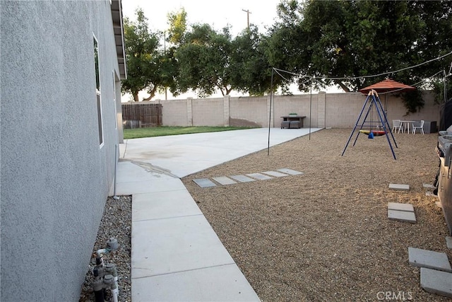 view of yard with a fenced backyard, a playground, and a patio
