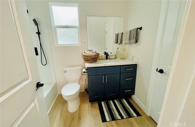 bathroom with toilet, baseboards, vanity, and wood finished floors