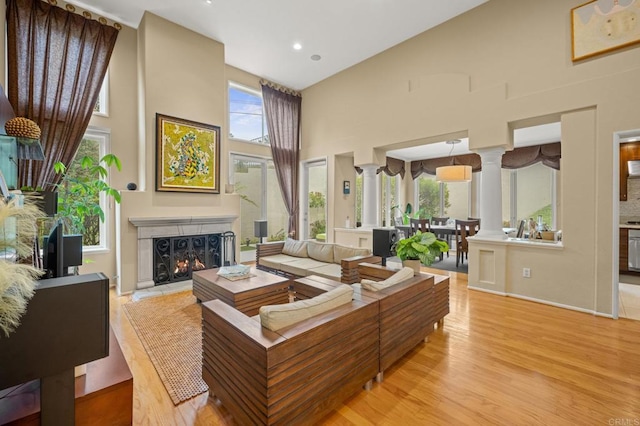 3358 Caminito Luna Nueva, Del Mar, CA 92014 - living room featuring decorative columns, a towering ceiling, plenty of natural light, light wood-style flooring, and a lit fireplace