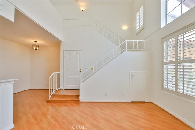 7100 La Tijera Blvd Unit B202, Los Angeles, CA 90045 - unfurnished living room featuring a towering ceiling, wood finished floors, stairway, and baseboards