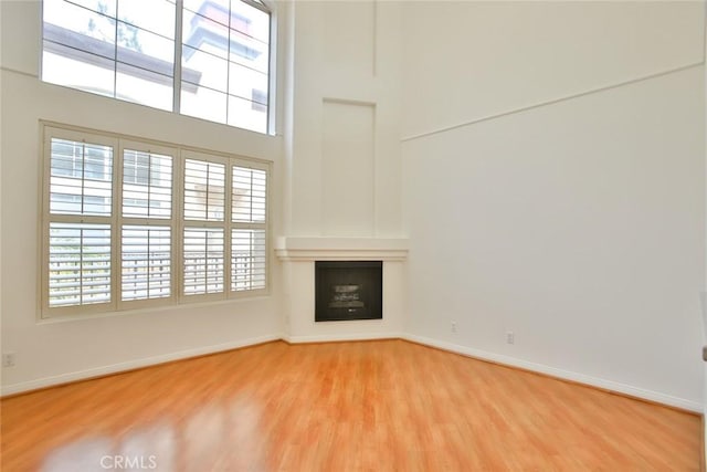 7100 La Tijera Blvd Unit B202, Los Angeles, CA 90045 - unfurnished living room with wood finished floors, baseboards, a fireplace, and a high ceiling