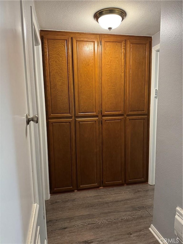 hallway featuring a textured ceiling and dark wood-type flooring