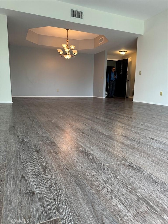 spare room featuring a tray ceiling, a notable chandelier, baseboards, and visible vents
