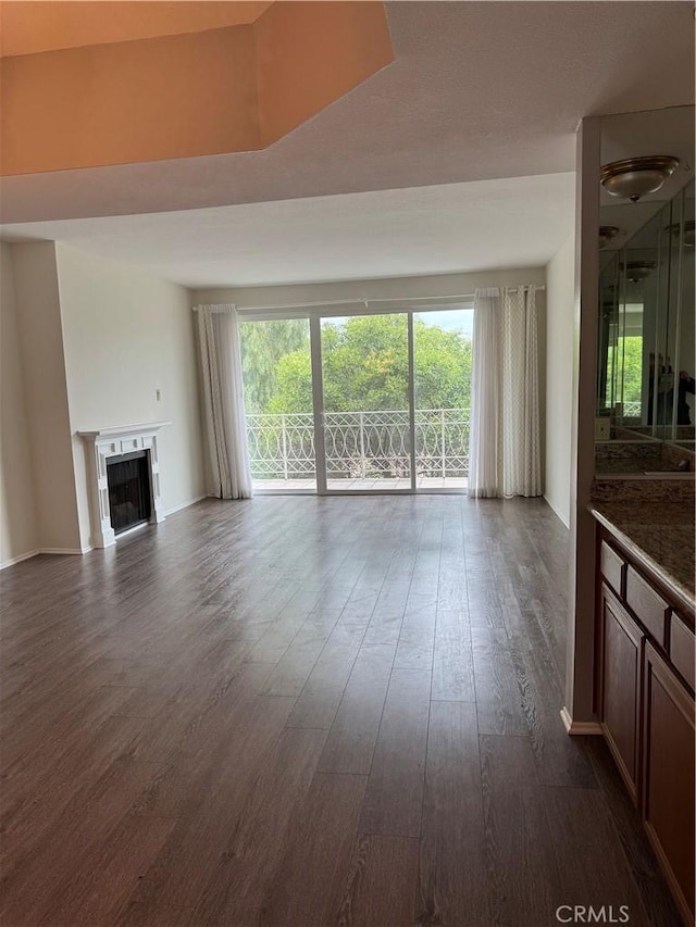 unfurnished living room with dark wood-style flooring, a healthy amount of sunlight, and a fireplace
